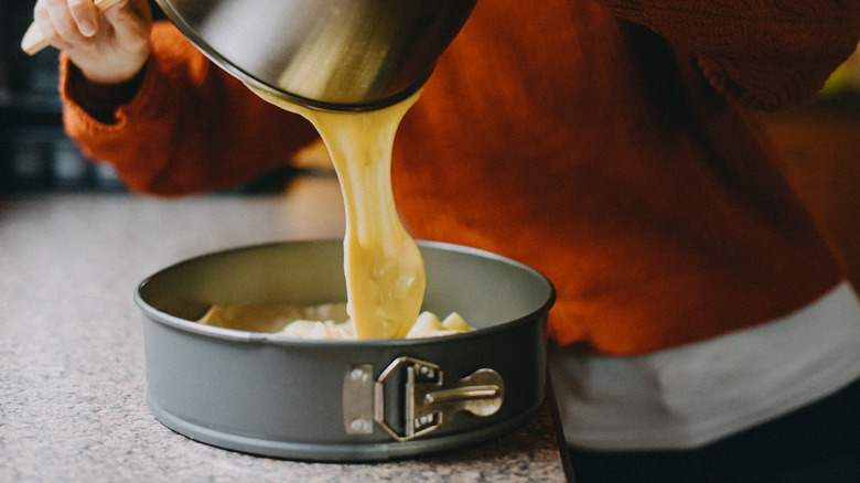 Person pouring cake batter into a springform pan